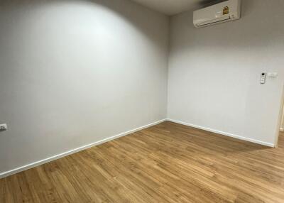 Empty bedroom with wooden flooring and air conditioner