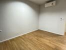 Empty bedroom with wooden flooring and air conditioner