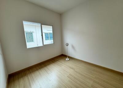 Unfurnished bedroom with a wooden floor, window, and a standing fan