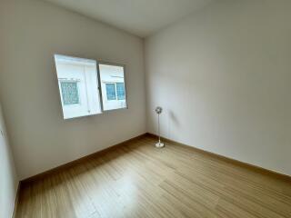 Unfurnished bedroom with a wooden floor, window, and a standing fan