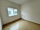 Unfurnished bedroom with a wooden floor, window, and a standing fan