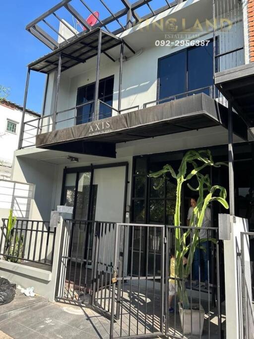 Modern two-story building exterior with balcony and gated entrance