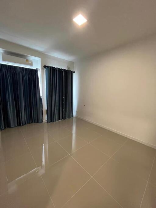 Empty bedroom with tiled floor and dark curtains