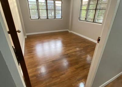 Spacious empty bedroom with polished wood flooring and large windows