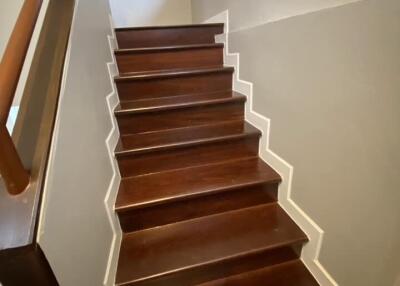 Wooden staircase with white trim and a railing