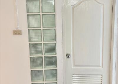 A white door with a panel of glass blocks beside it