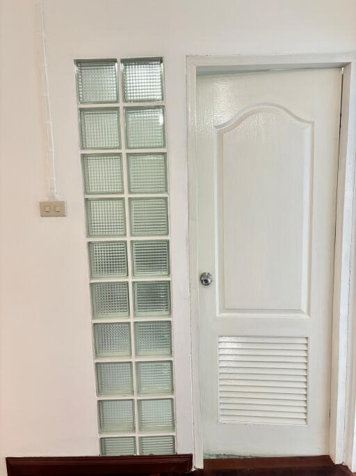 A white door with a panel of glass blocks beside it