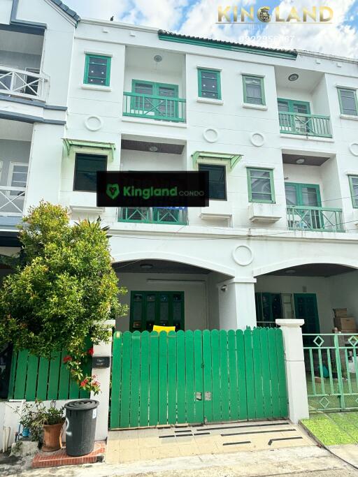 Front view of a three-story townhouse with green and white exterior