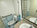 Small bathroom with tiled walls, a round vanity sink, and a toilet.