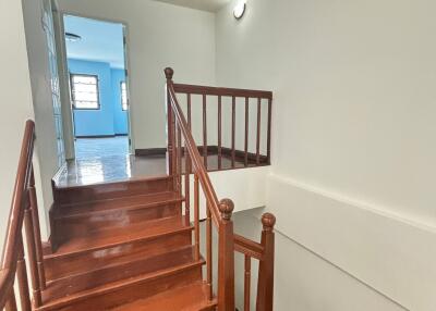 Polished wooden staircase with white walls leading to a well-lit room