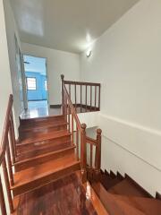 Polished wooden staircase with white walls leading to a well-lit room