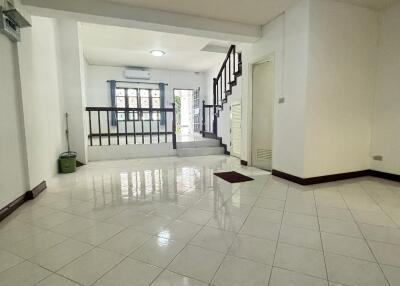 Spacious living room with bright tiles, staircase, and large windows