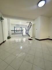 Spacious living room with bright tiles, staircase, and large windows