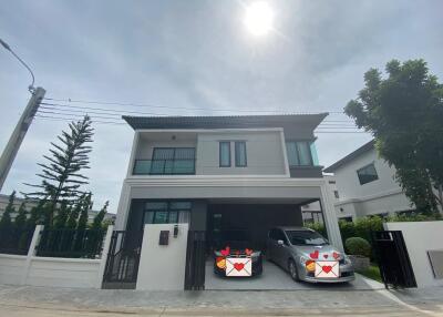 Front view of a modern two-story house with a gated driveway and two cars parked.