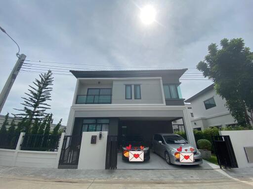 Front view of a modern two-story house with a gated driveway and two cars parked.