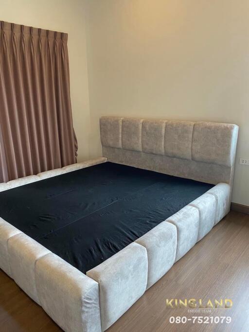 Spacious bedroom with a large grey upholstered bed and brown curtains