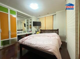 Spacious bedroom with large bed, television, and wardrobe