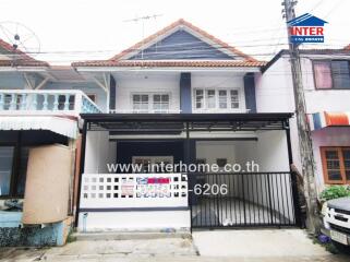 Photo of the exterior view of a house with a small carport and balcony