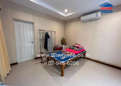 Spacious bedroom with clothes rack, air conditioner, and neatly arranged bed with folded clothes