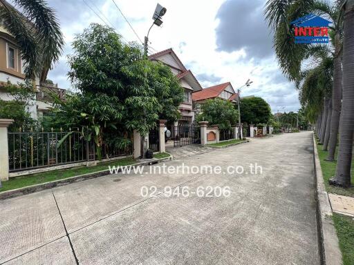 Street view of residential buildings with lush greenery