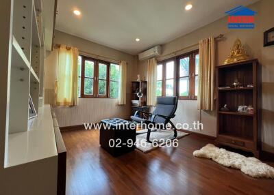 Cozy living room with wooden floors, bookshelf, and large windows