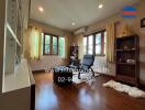 Cozy living room with wooden floors, bookshelf, and large windows