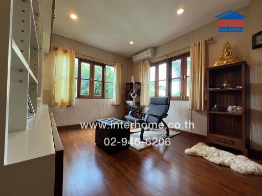 Cozy living room with wooden floors, bookshelf, and large windows