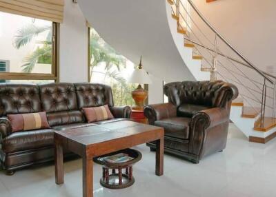 Cozy living room with brown leather furniture and a staircase