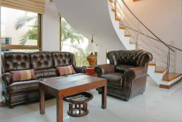 Cozy living room with brown leather furniture and a staircase