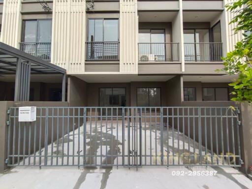 Exterior view of a modern multi-story building with a gated driveway