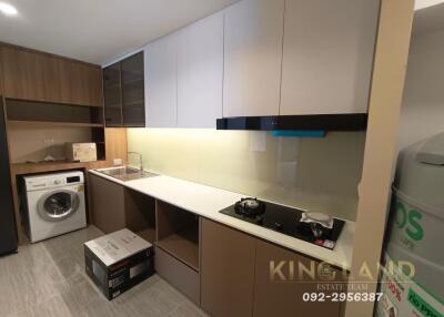 Modern kitchen with wooden cabinets, built-in stove, and washer