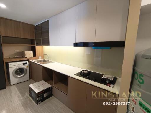 Modern kitchen with wooden cabinets, built-in stove, and washer