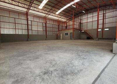 Spacious warehouse interior with concrete floor and high ceiling.