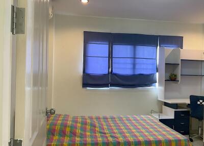 Bedroom with a colorful bed, blue curtains, and a work desk