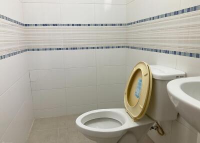 Bathroom with toilet, sink, and tiled walls