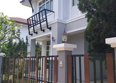 Exterior view of a modern two-story house with a gated front yard