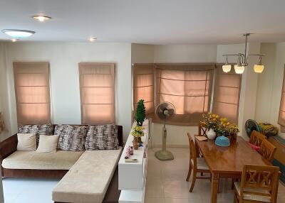 Living room with brown sectional sofa, dining table, and windows with beige curtains