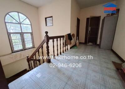 Staircase area with window, tiled floor, and banister