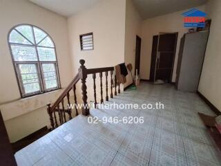 Staircase area with window, tiled floor, and banister