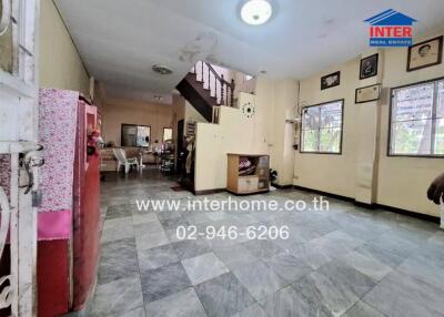 Spacious living room with tiled flooring, staircase, and large windows