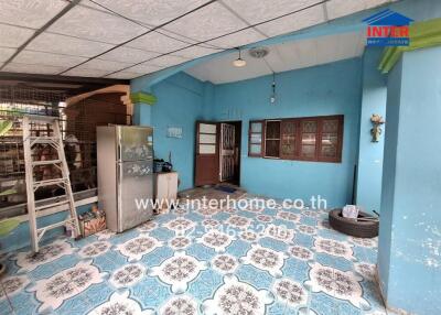 Covered porch area with blue walls, patterned floor tiles, and various household items