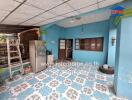 Covered porch area with blue walls, patterned floor tiles, and various household items