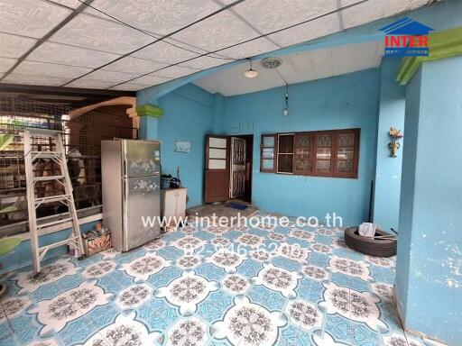 Covered porch area with blue walls, patterned floor tiles, and various household items