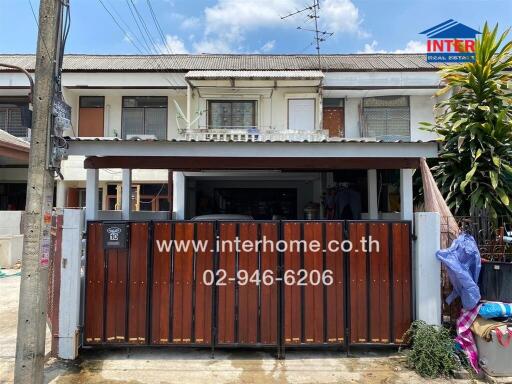 Two-story house facade with fenced yard