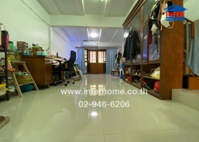 Spacious living room with office setup, tile flooring, and storage