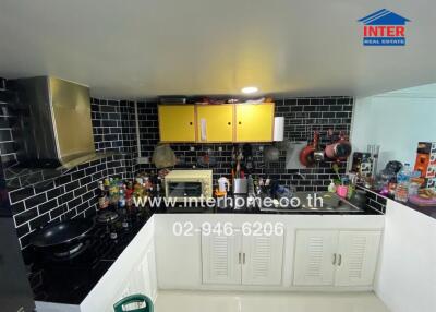 Modern kitchen with black tiled backsplash and yellow cabinets