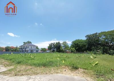 Vacant lot with blue sky and neighboring houses