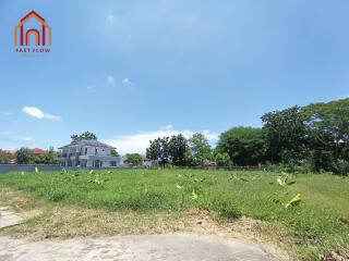 Vacant lot with blue sky and neighboring houses