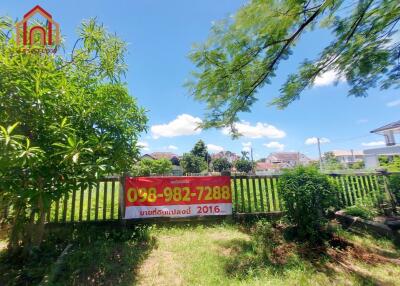 Front yard with a fence and a for sale sign, surrounded by greenery