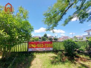 Front yard with a fence and a for sale sign, surrounded by greenery